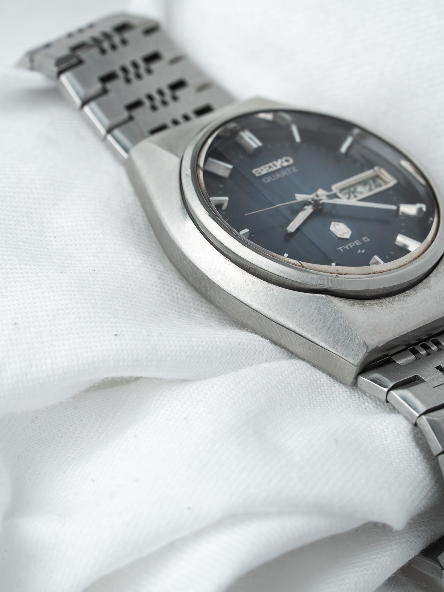 Seiko Quartz Type II vintage watch with dark dial and steel bracelet on white fabric