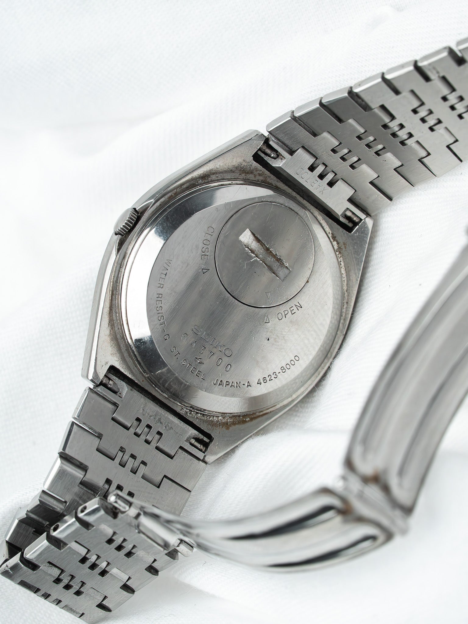 Vintage Seiko 43700 watch back, stainless steel case and bracelet on white fabric