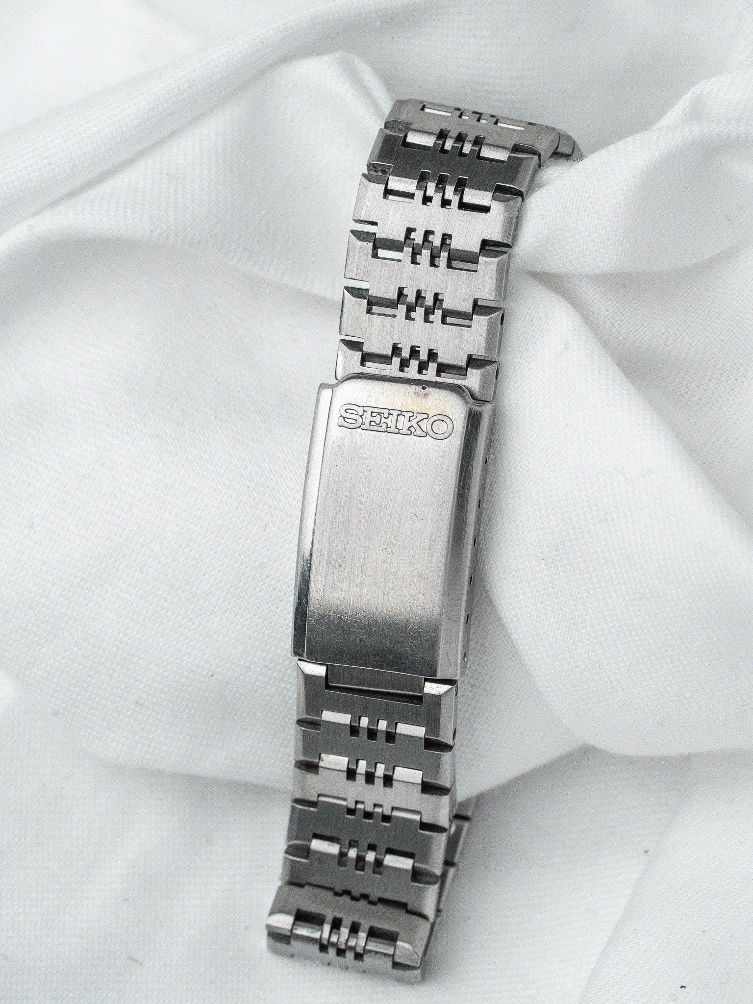 Seiko vintage watch bracelet in stainless steel with engraved clasp on white fabric