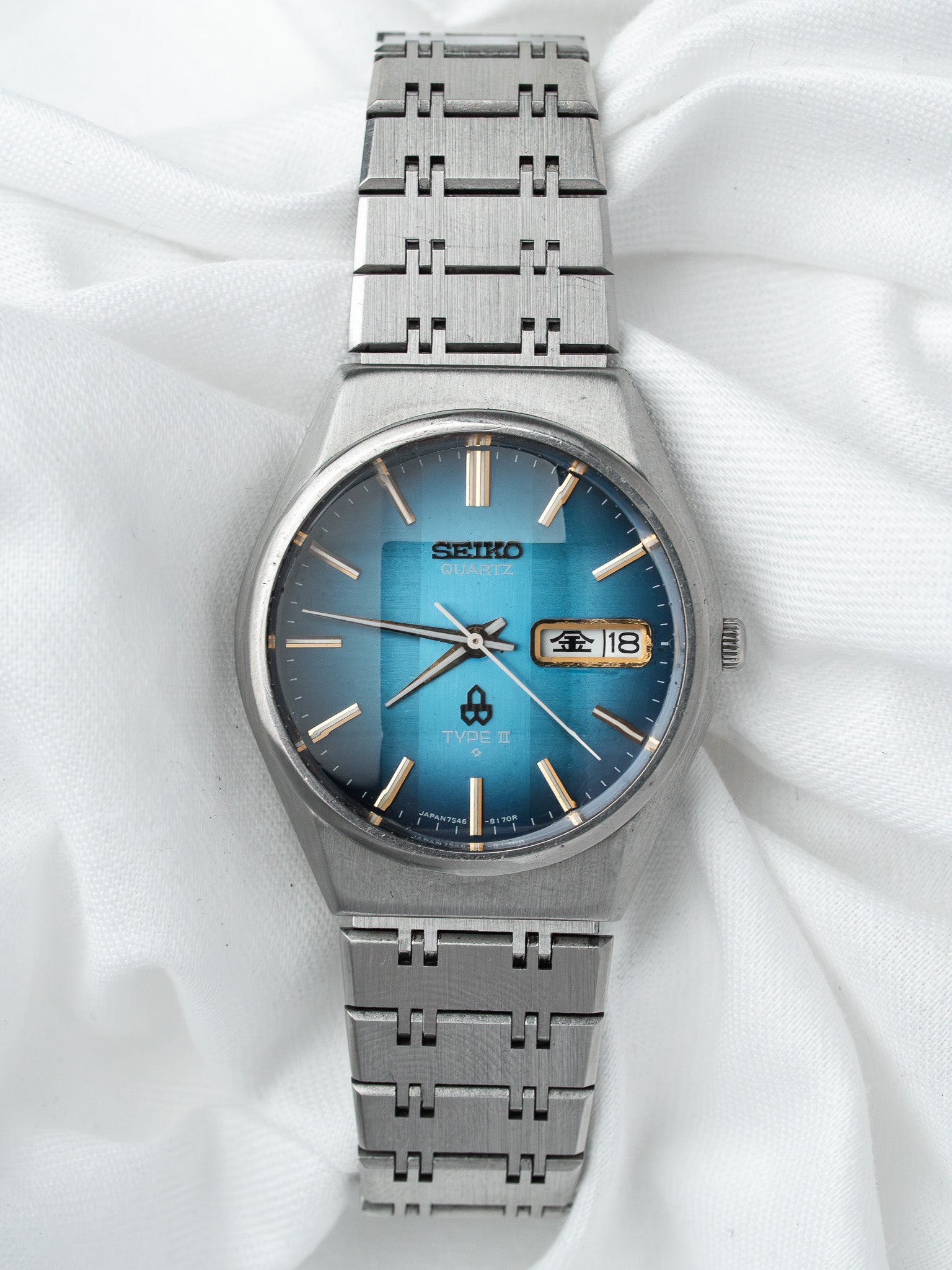 Seiko Type II vintage quartz watch with blue gradient dial and steel bracelet on white fabric