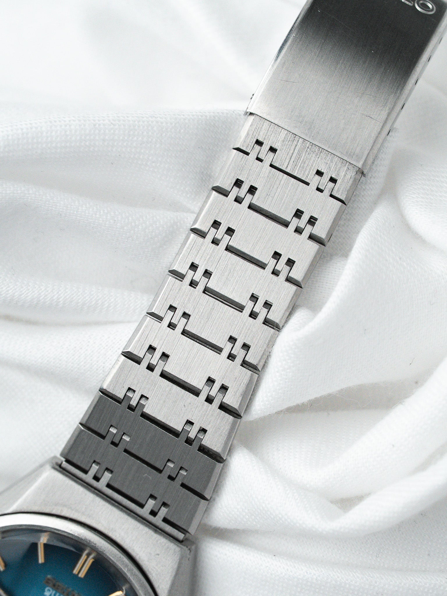 Seiko vintage watch with blue dial and distinctive stainless steel bracelet on white fabric