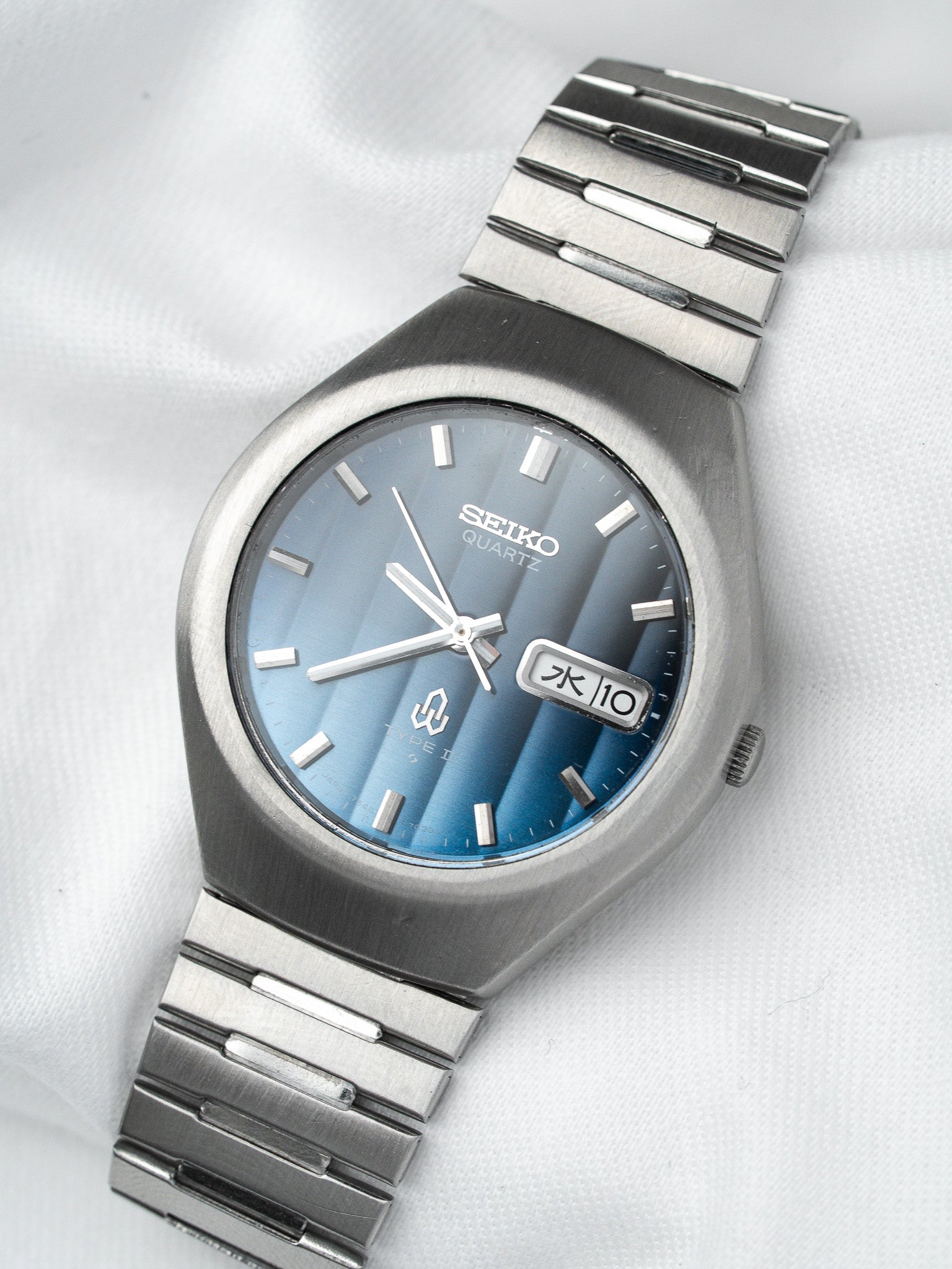 Seiko quartz vintage watch with blue gradient dial and steel bracelet on white fabric