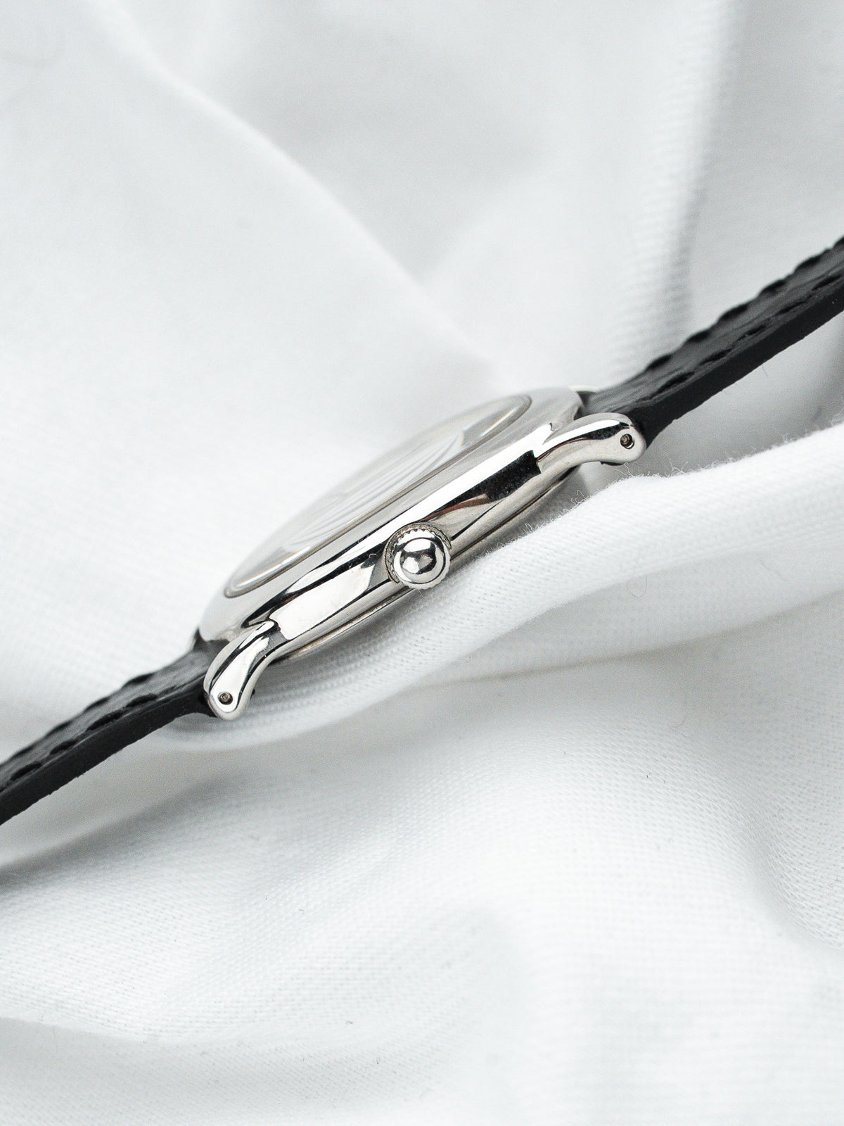Montre vintage en acier avec bracelet en cuir noir sur fond de tissu blanc
