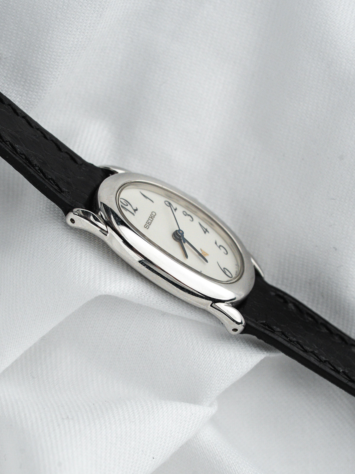Montre Seiko vintage au boîtier ovale argenté et bracelet en cuir noir