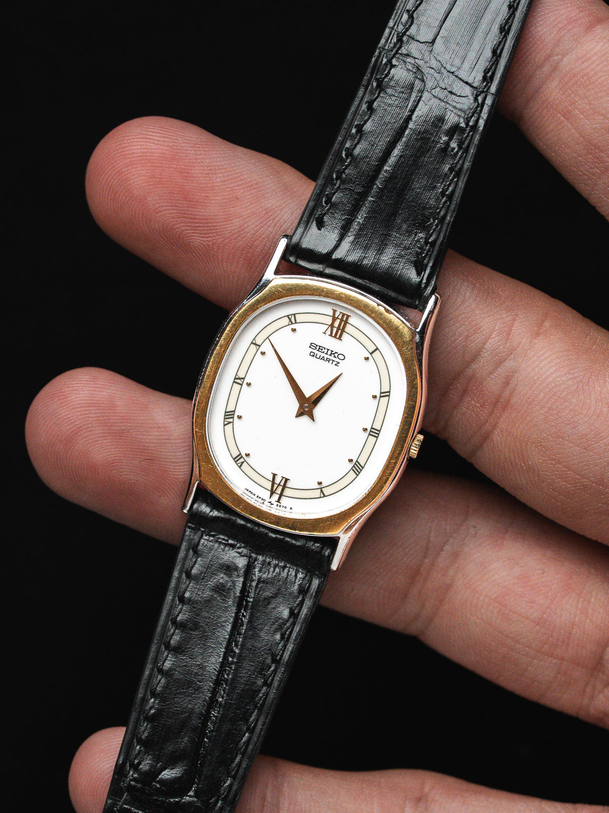 Montre Seiko Quartz vintage, boîtier ovale doré, cadran blanc et bracelet cuir noir