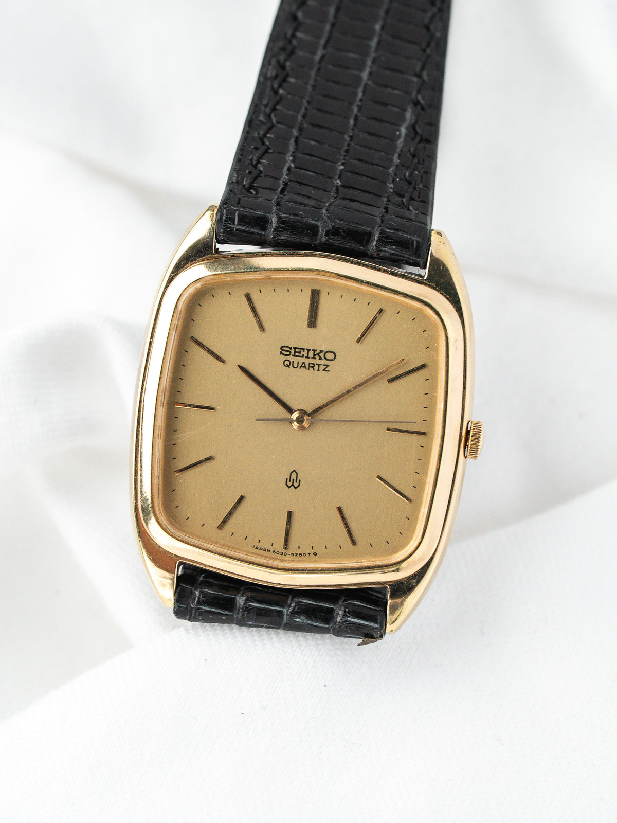 Montre Seiko Quartz vintage, boîtier doré rectangulaire, cadran champagne et bracelet cuir noir