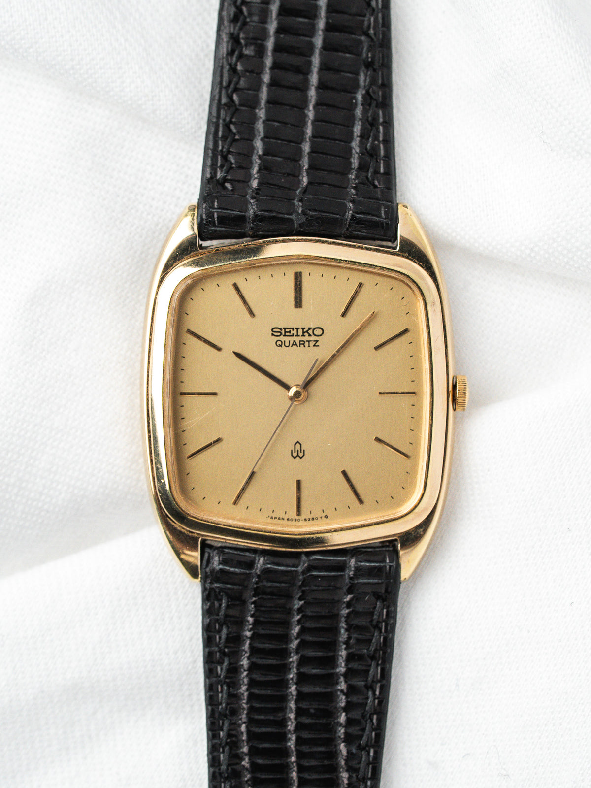 Montre Seiko Quartz vintage, boîtier rectangulaire doré, cadran champagne et bracelet cuir noir