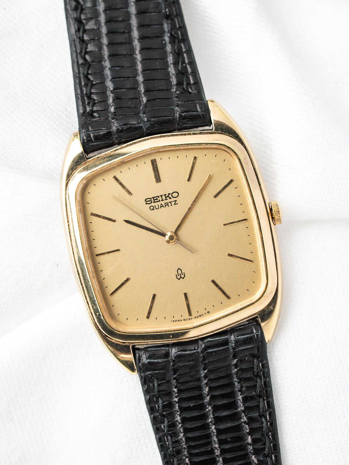 Montre Seiko Quartz vintage, boîtier rectangulaire doré, cadran champagne et bracelet cuir noir