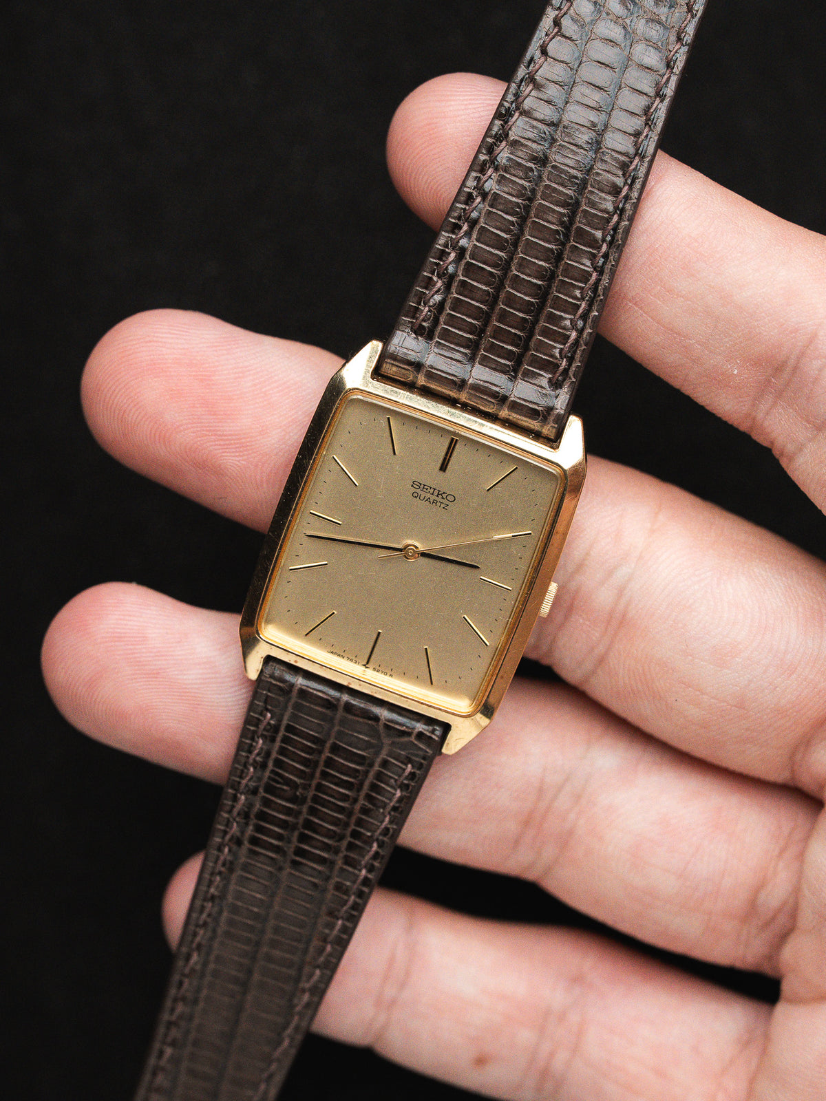 Seiko Quartz vintage watch with gold case, brown lizard strap, held in hand