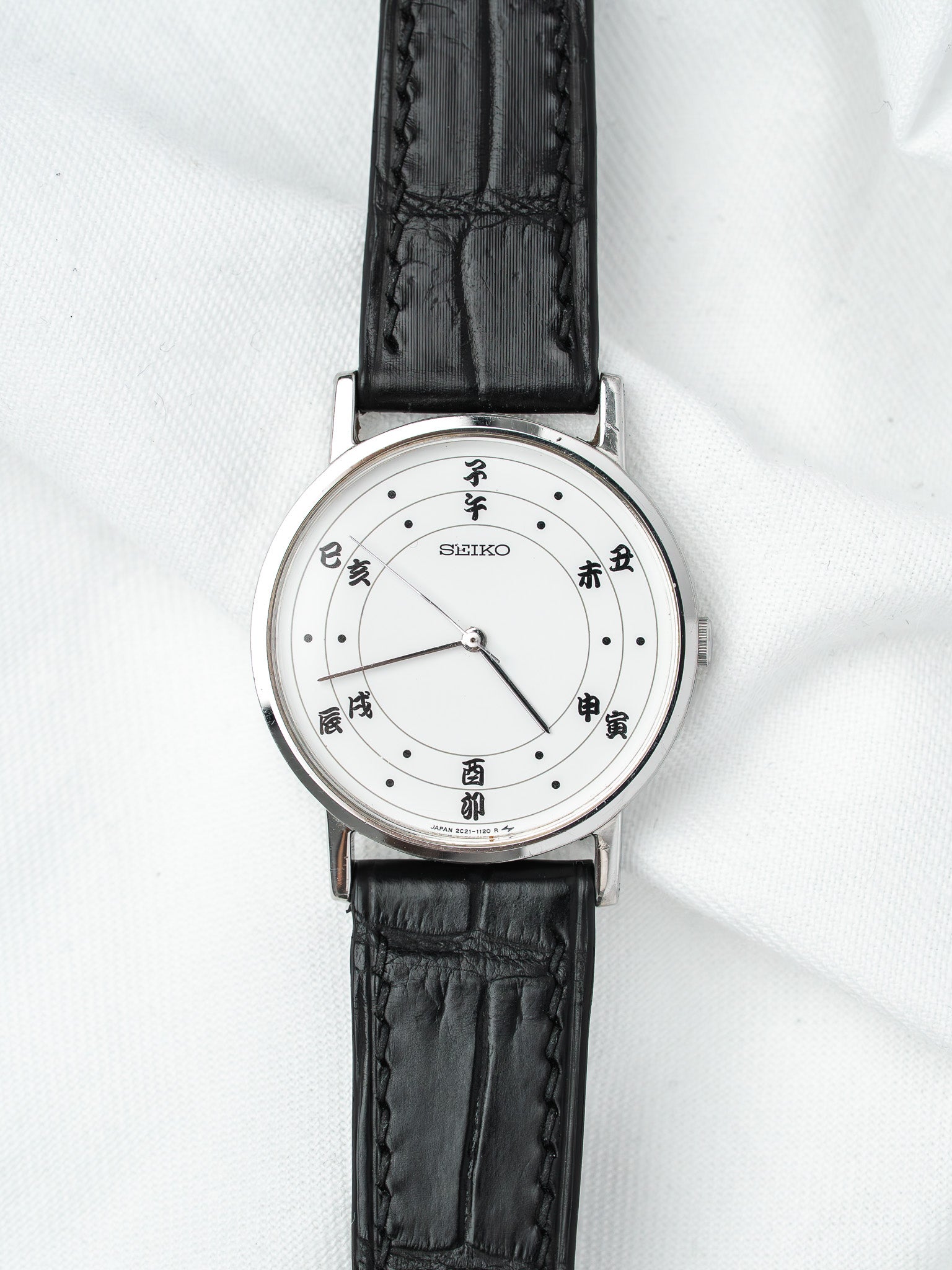 Seiko vintage watch with white dial, Japanese characters, black leather strap on white background