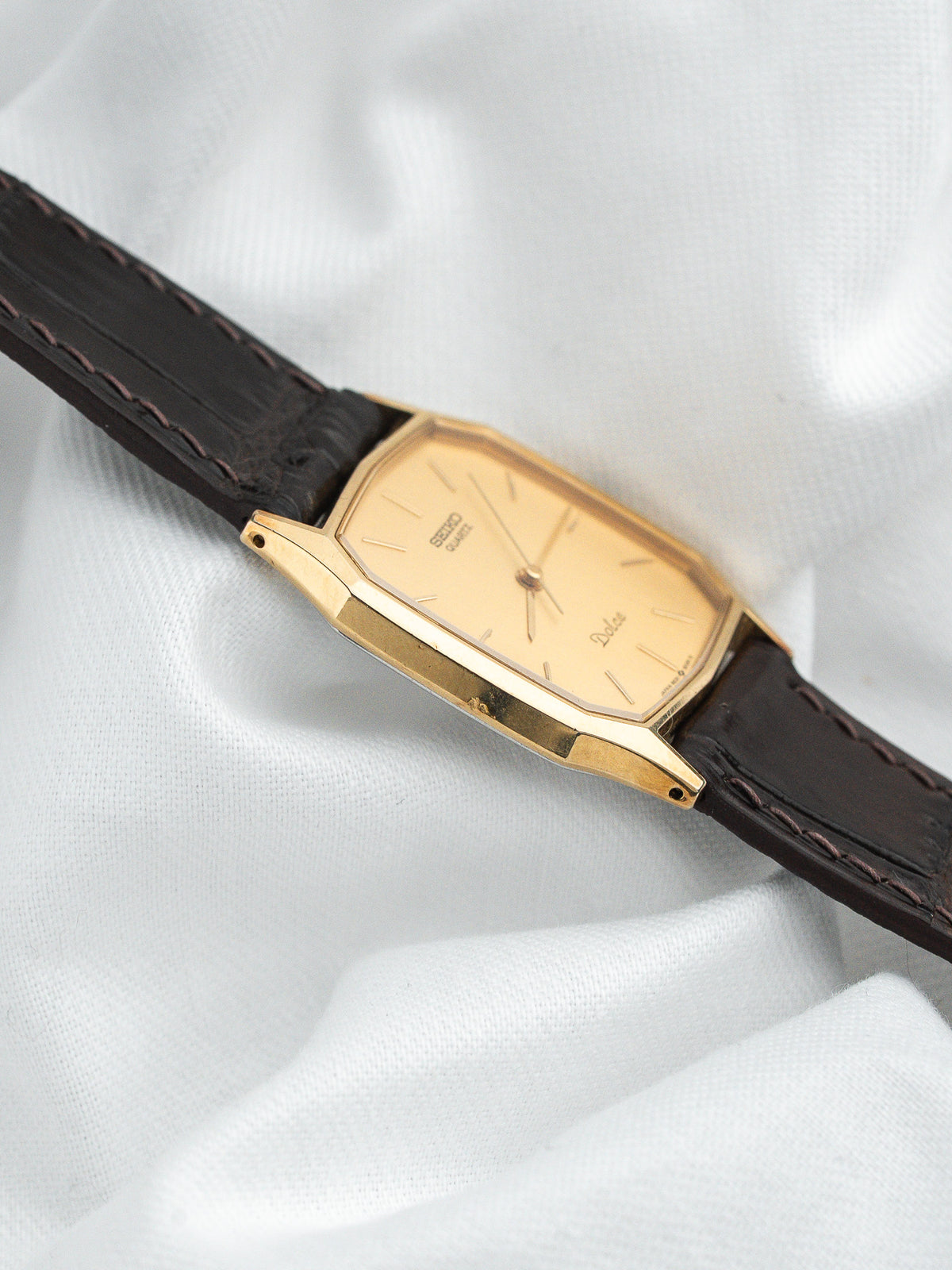 Montre Seiko Dolce vintage, boîtier rectangulaire doré, cadran champagne et bracelet cuir marron