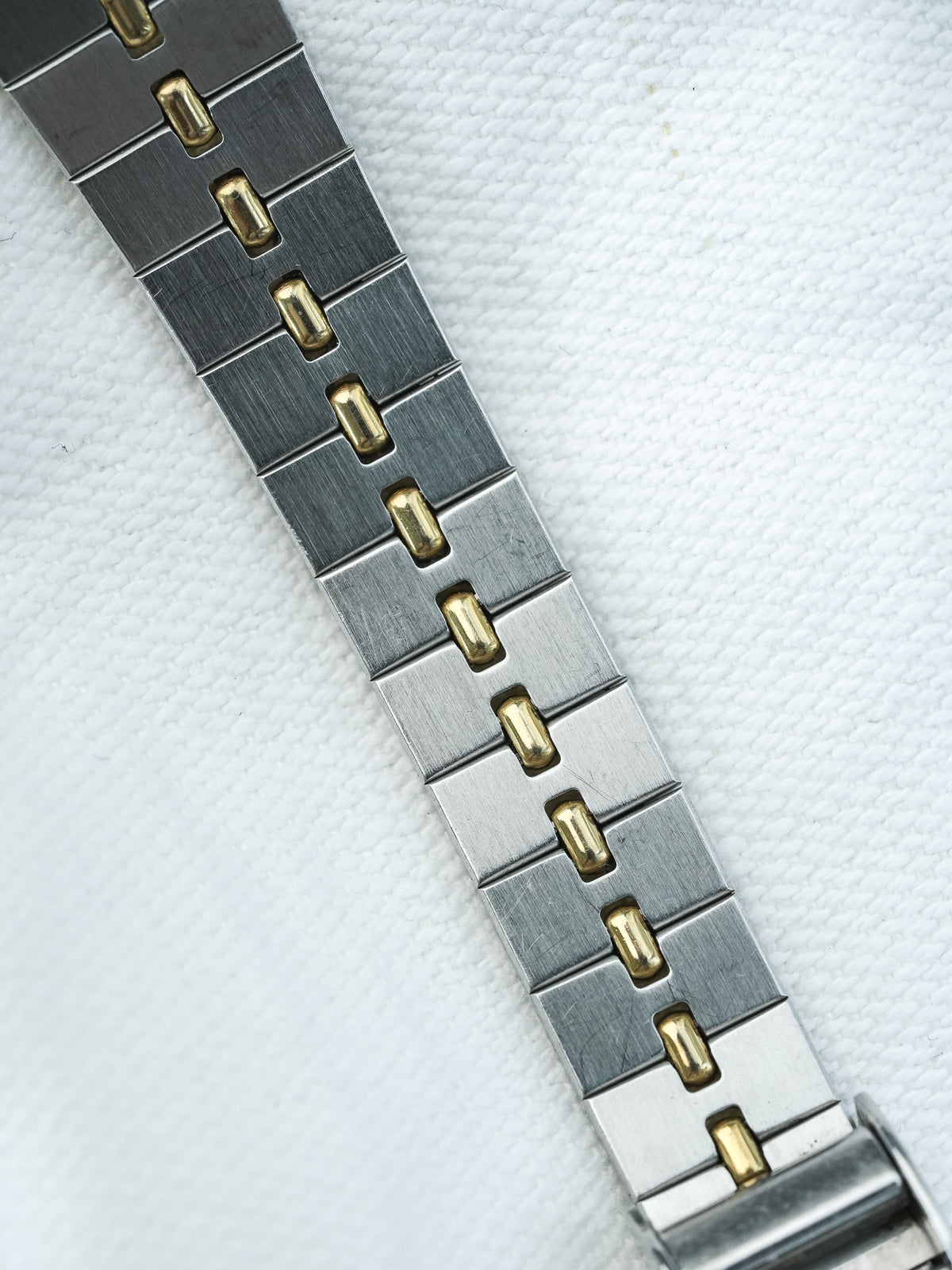 Vintage Rolex two-tone bracelet with brushed steel and gold center links on white fabric