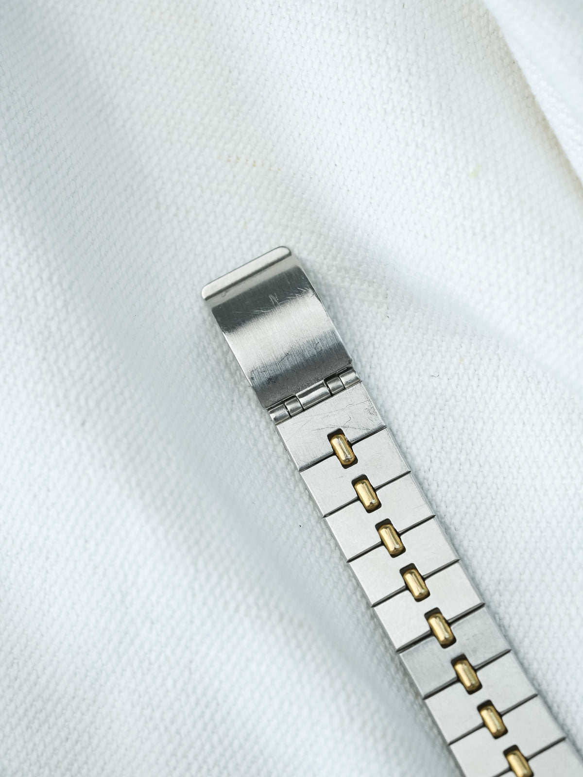 Vintage Rolex Oyster bracelet in stainless steel with gold center links on white fabric