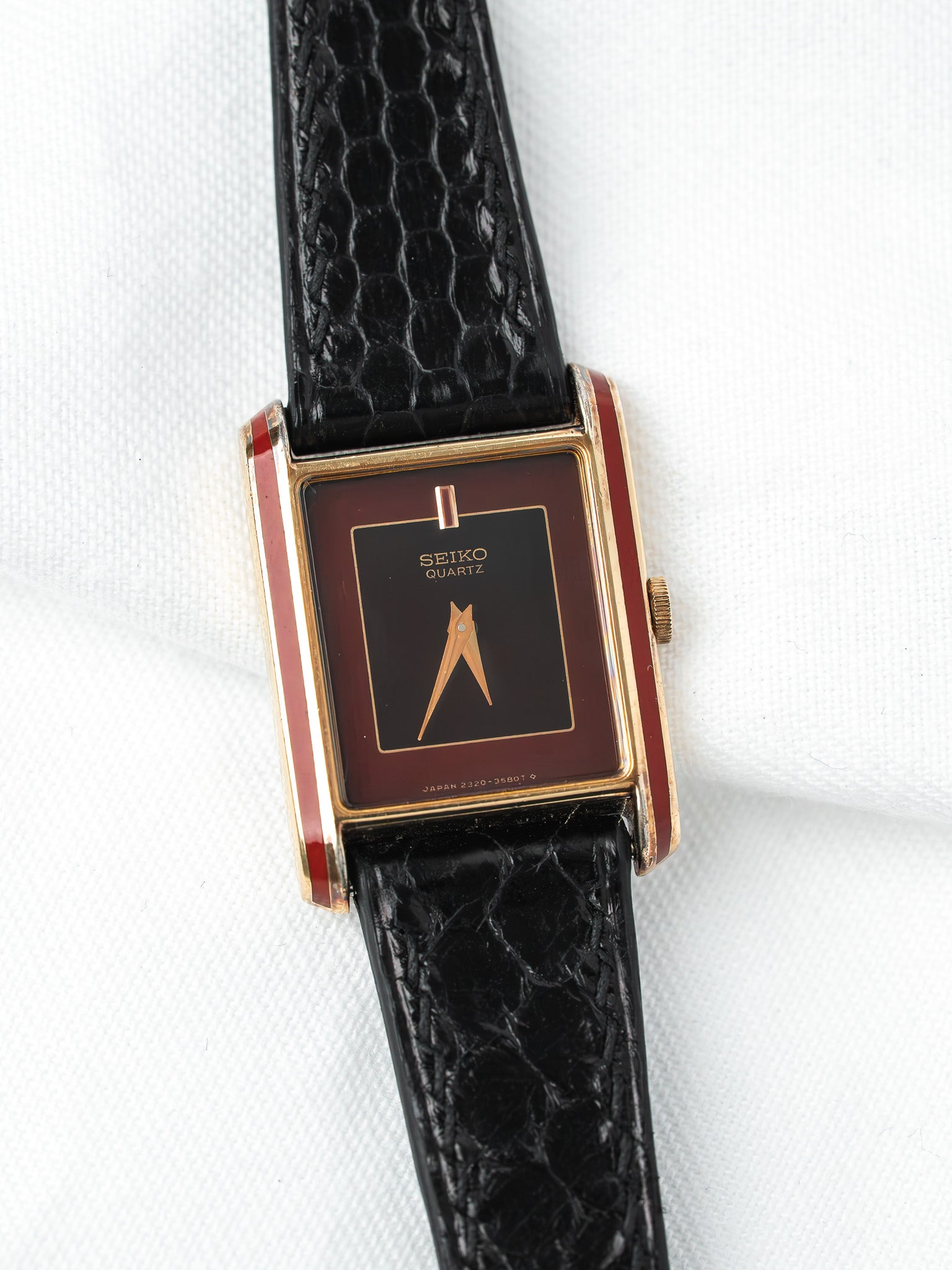 Seiko Quartz vintage watch with red enamel case, black dial, and textured black strap
