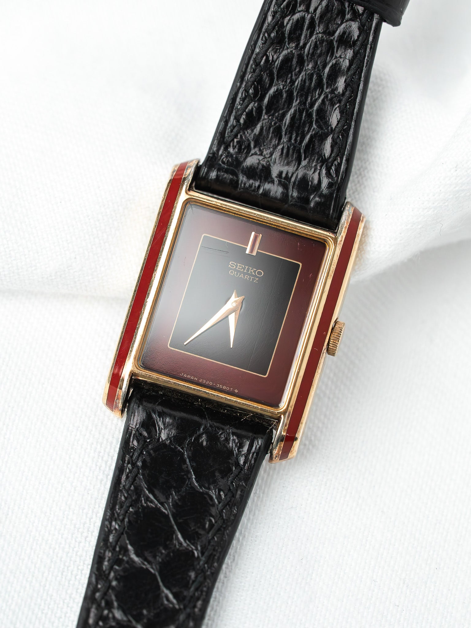 Seiko Quartz vintage watch with red enamel case, black dial, gold hands, and black alligator strap