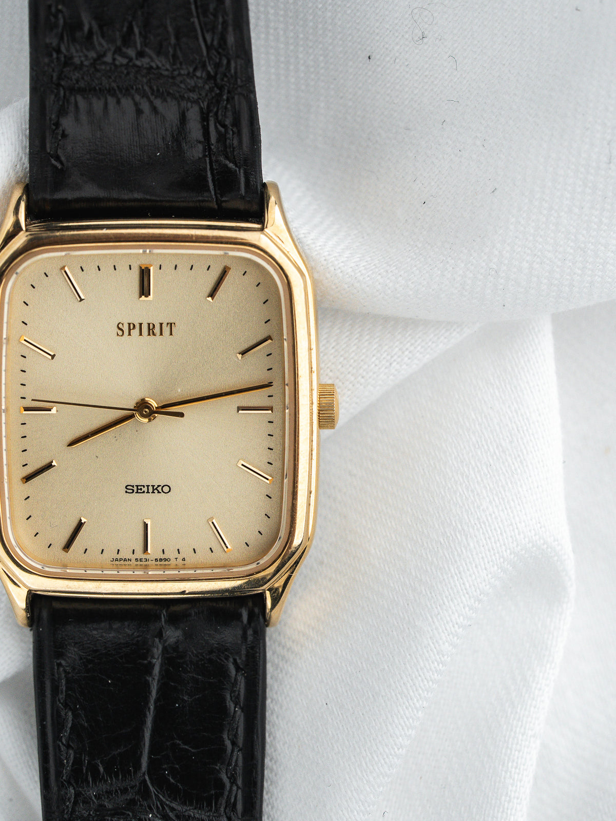 Montre Seiko Spirit vintage, boîtier rectangulaire doré, cadran champagne et bracelet cuir noir