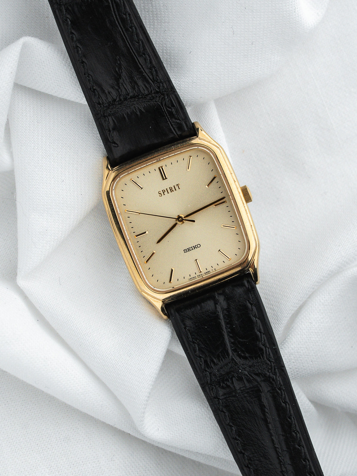 Montre Seiko Spirit vintage, boîtier rectangulaire doré, cadran champagne et bracelet cuir noir
