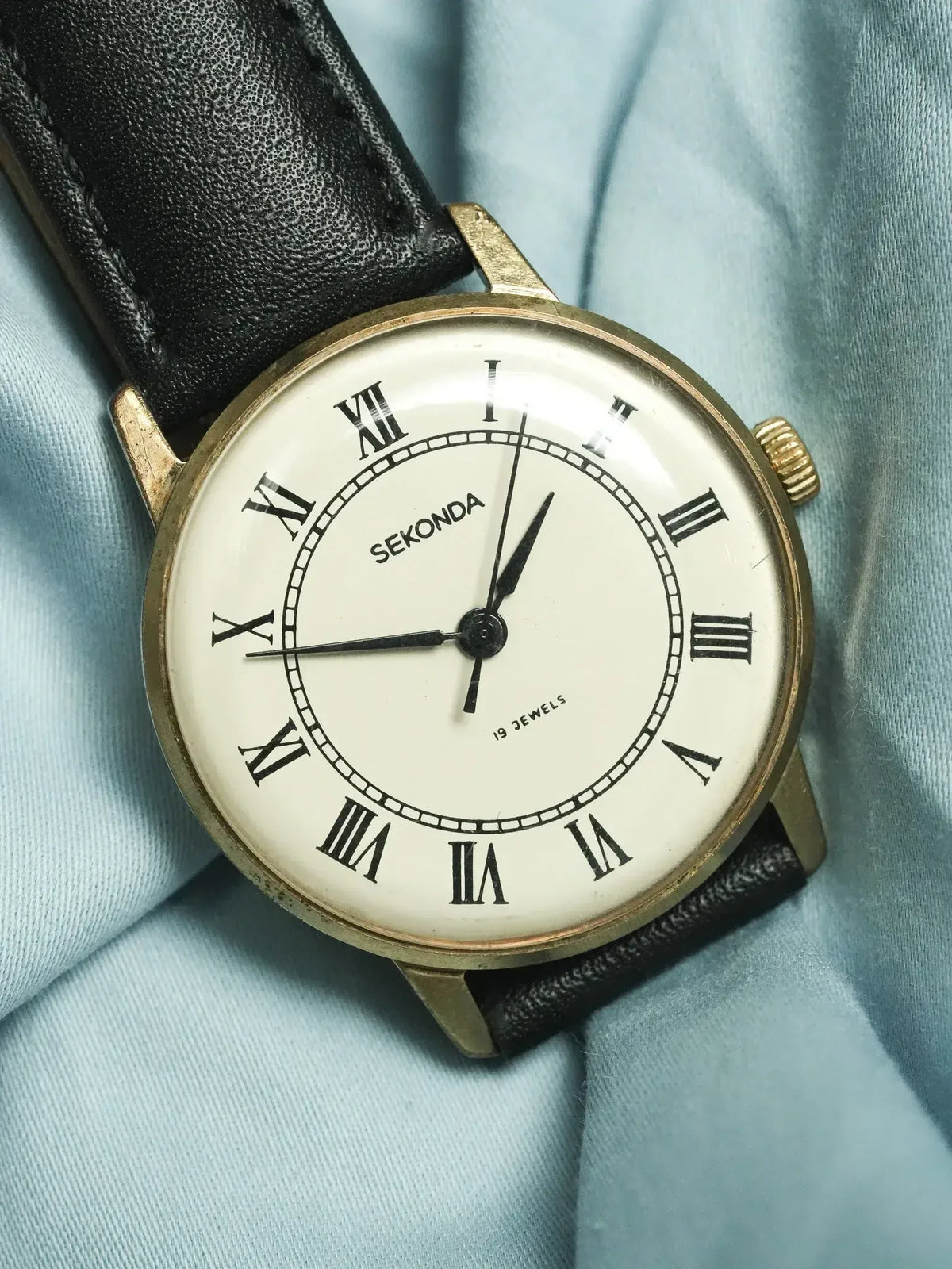 Sekonda vintage watch with gold case, white dial, Roman numerals, black leather strap