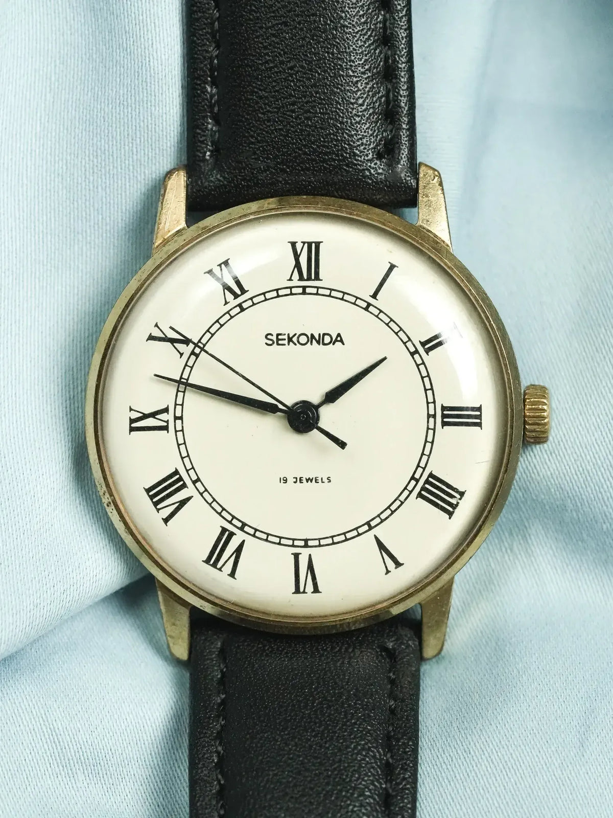 Vintage Sekonda watch with gold case, white dial, Roman numerals, black leather strap