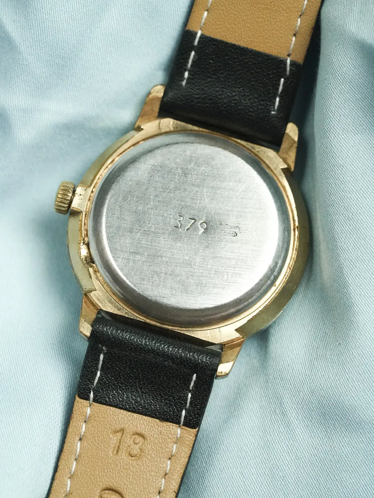 Vintage watch with gold case, black and tan leather strap, case back engraved 379
