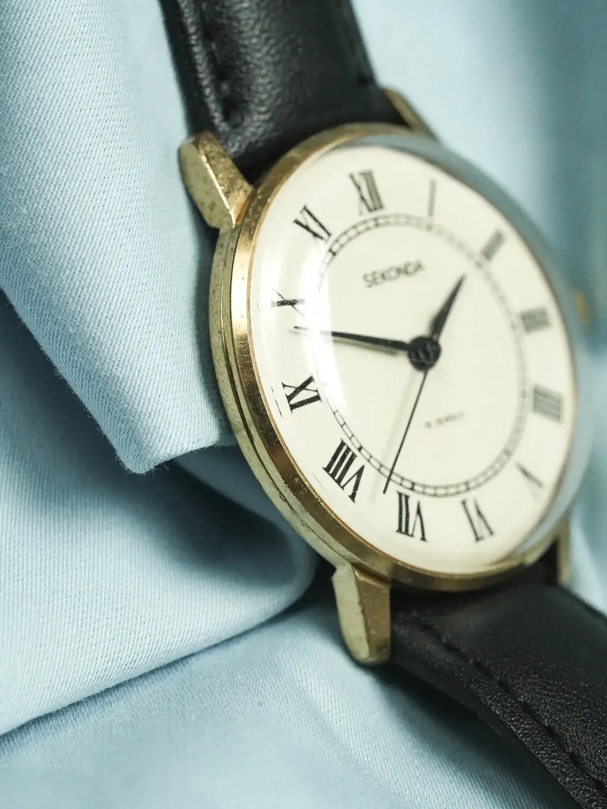 Seiko vintage watch with gold case, white dial, Roman numerals, black leather strap