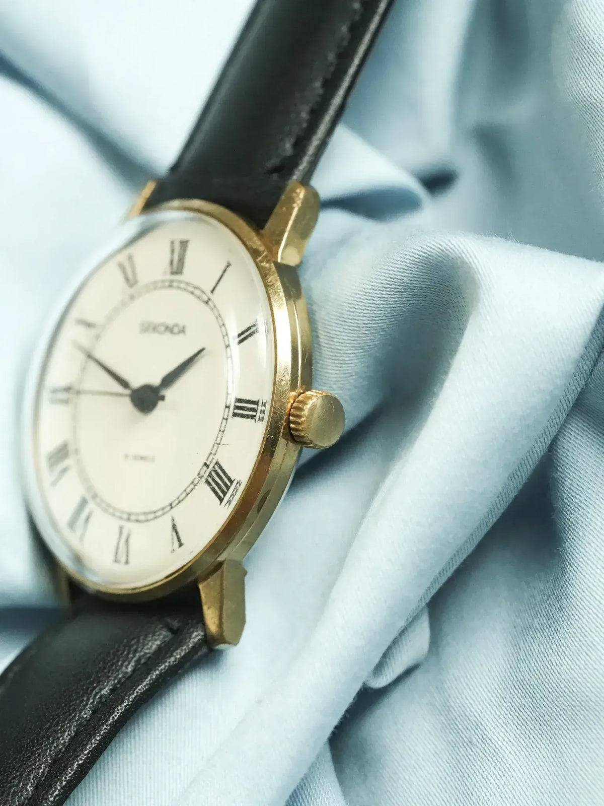 Seiko vintage watch with gold case, white dial, Roman numerals, black leather strap