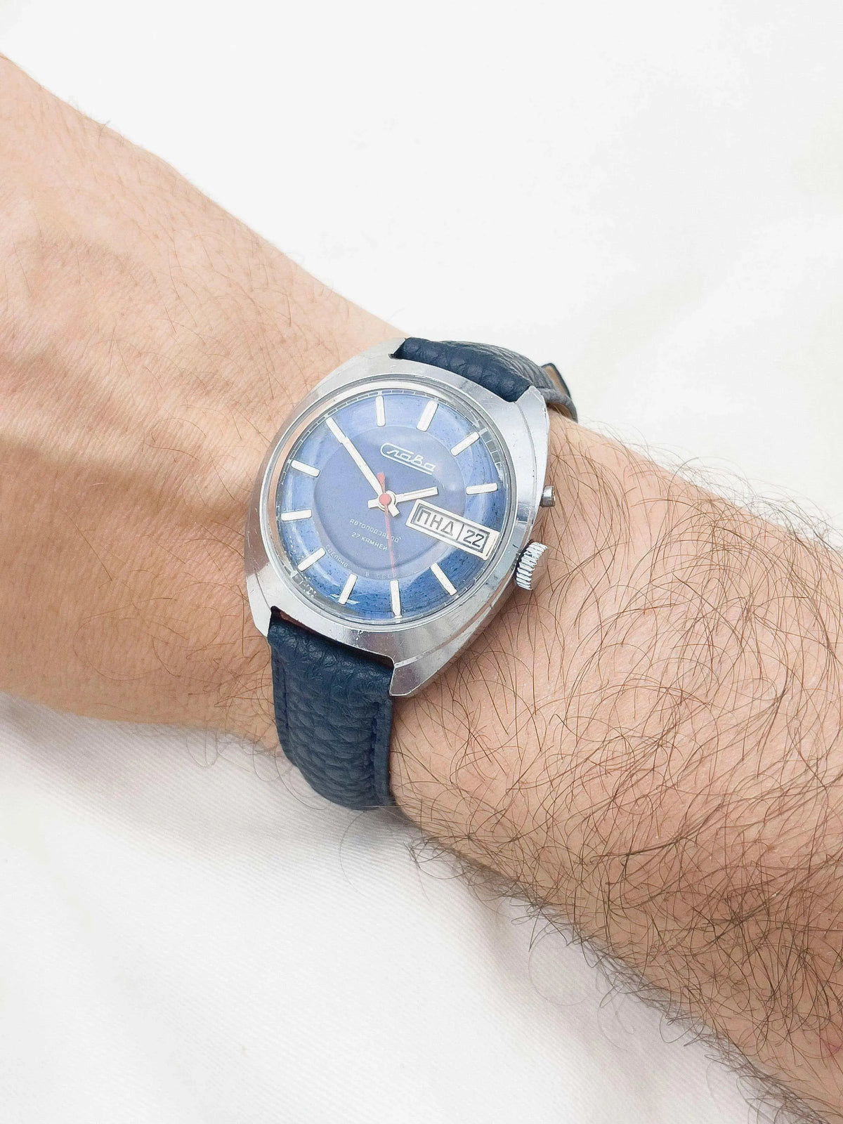 Vintage Vostok watch with blue dial, steel case, and textured strap worn on wrist