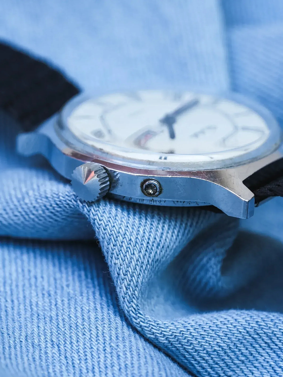 Vintage Seiko watch with silver case, white dial, black strap on denim
