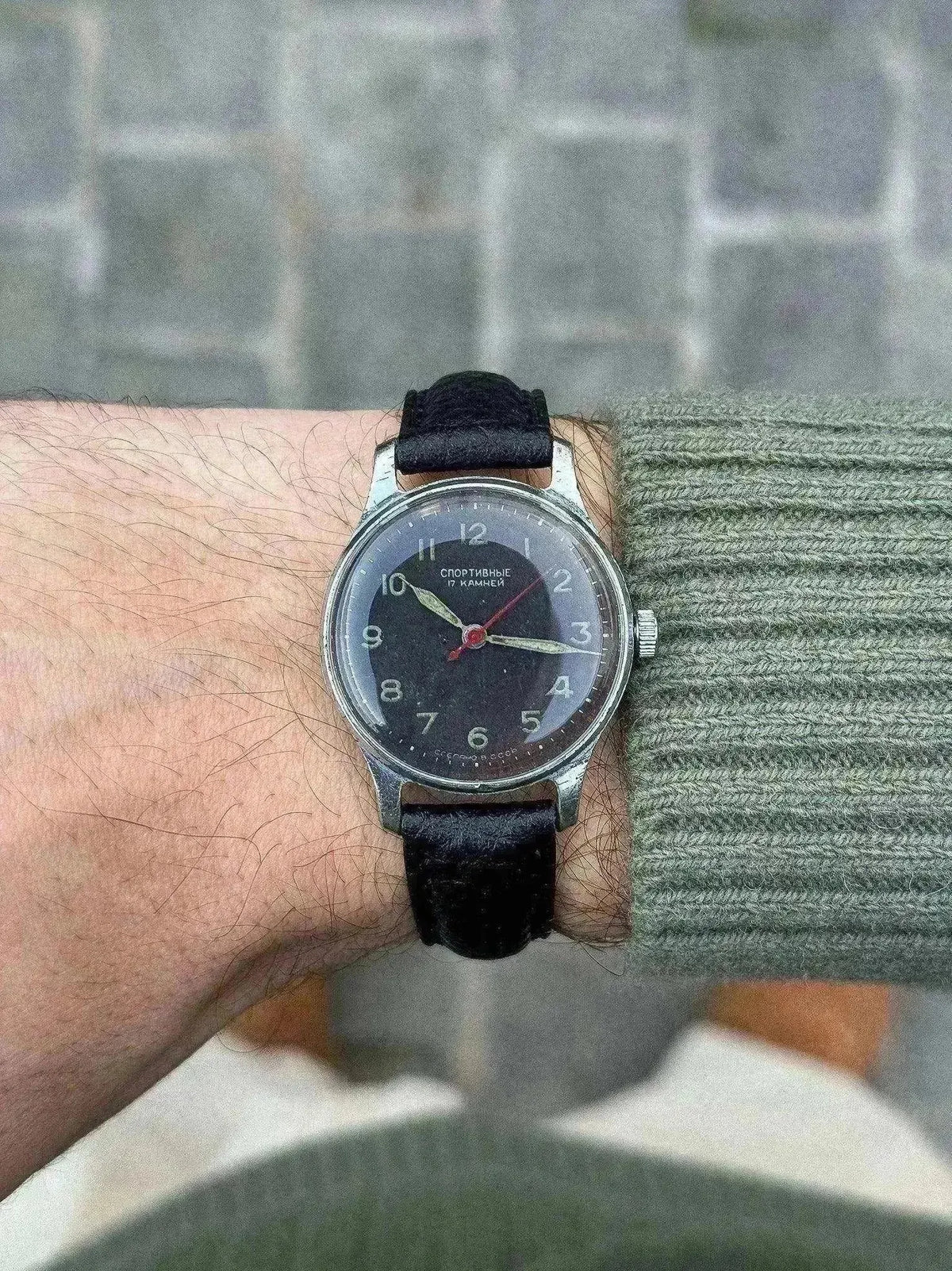 Vintage Soviet Sportivnye watch with black dial, silver case, and black strap worn on wrist