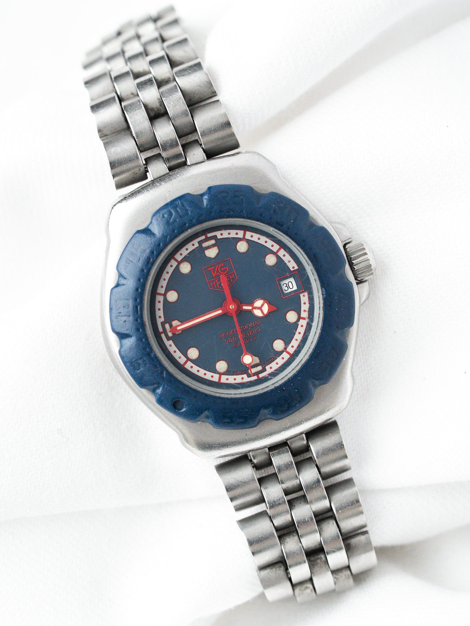 TAG Heuer Professional vintage watch with blue dial, red accents, and steel bracelet
