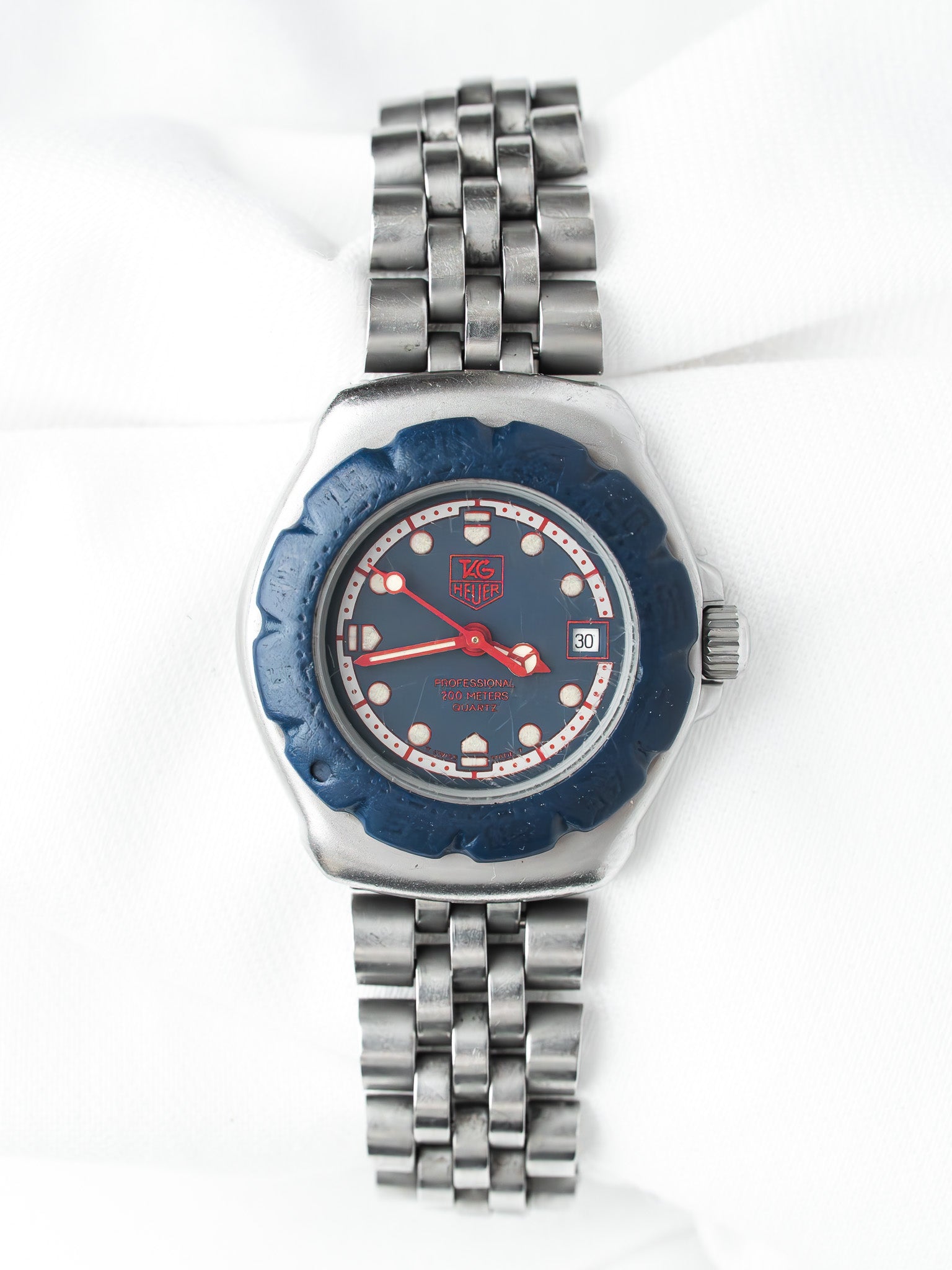 TAG Heuer vintage watch with blue dial, red accents, and steel bracelet