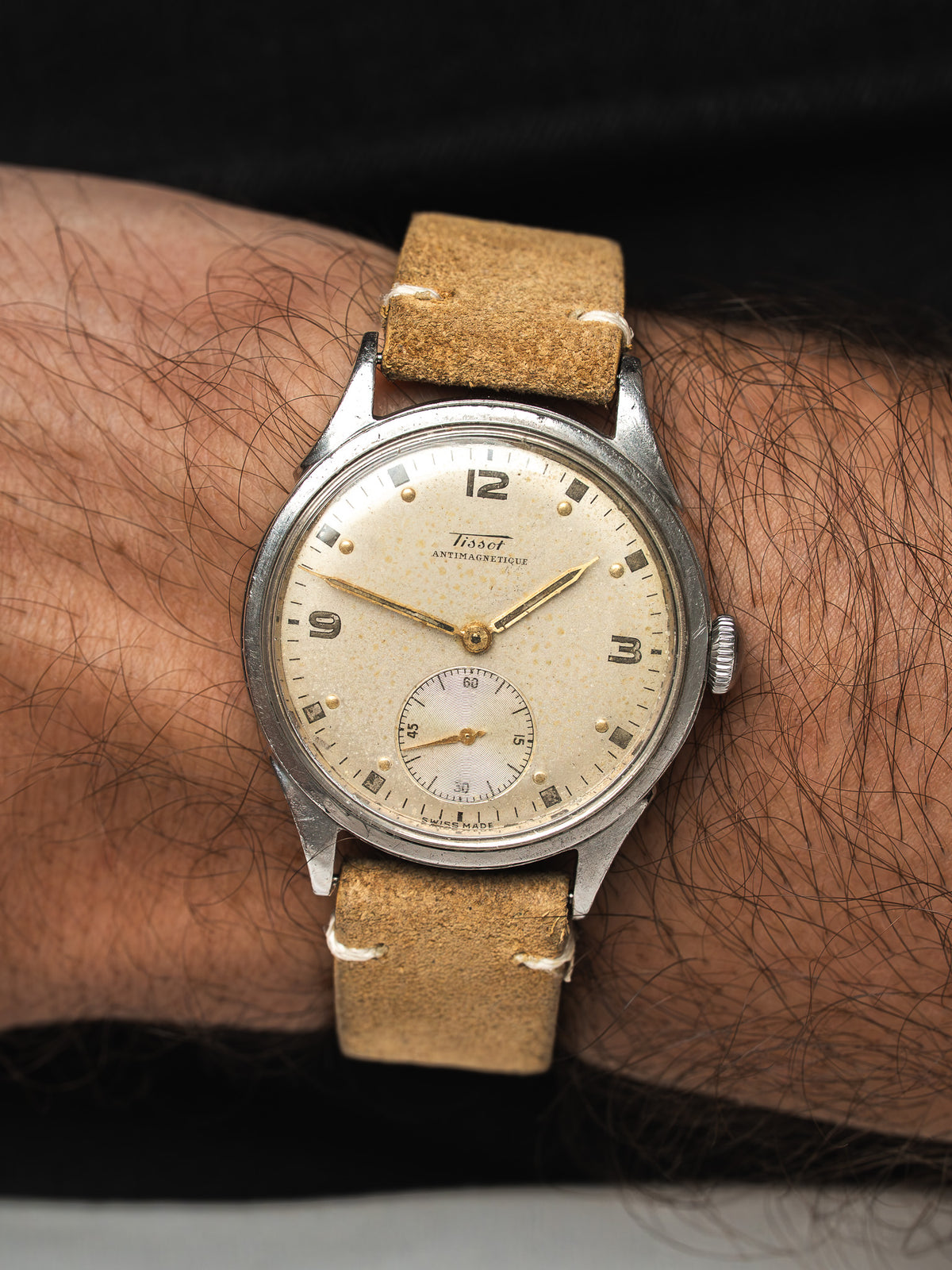 Montre Tissot vintage en acier, cadran crème et bracelet cuir beige, portée au poignet