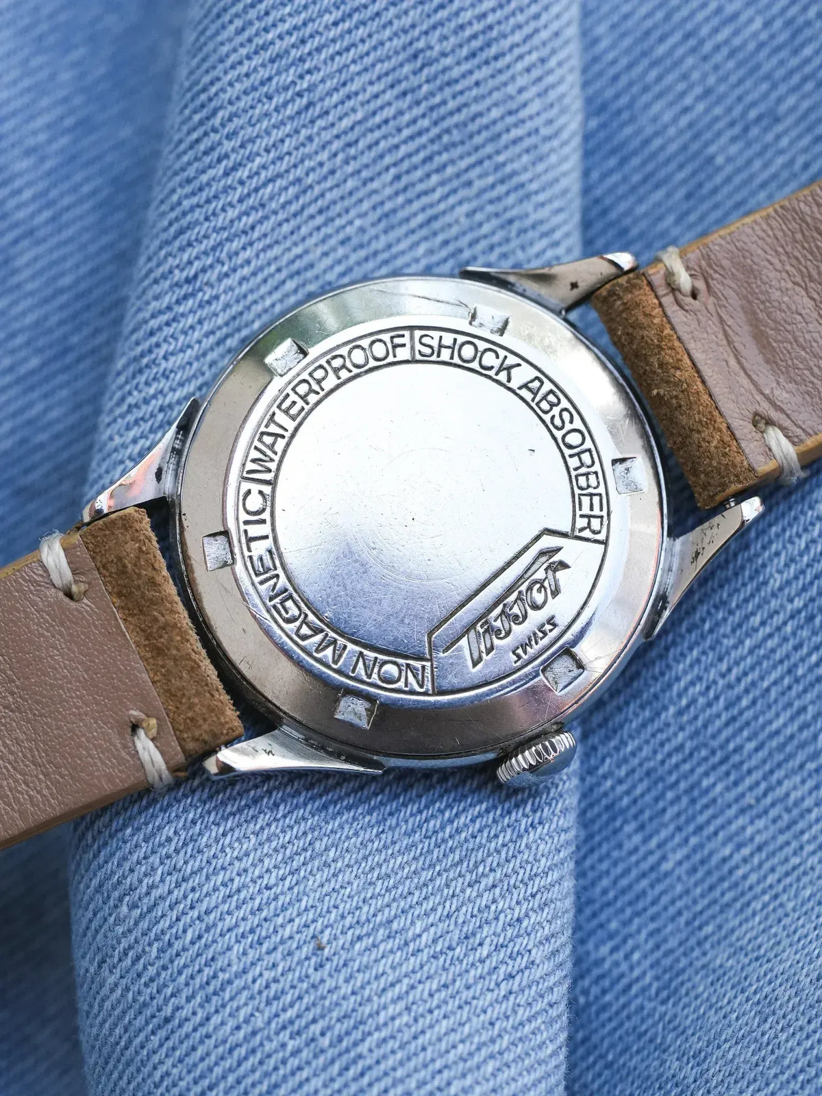 Tissot vintage watch back with engraved waterproof shock absorber text on denim