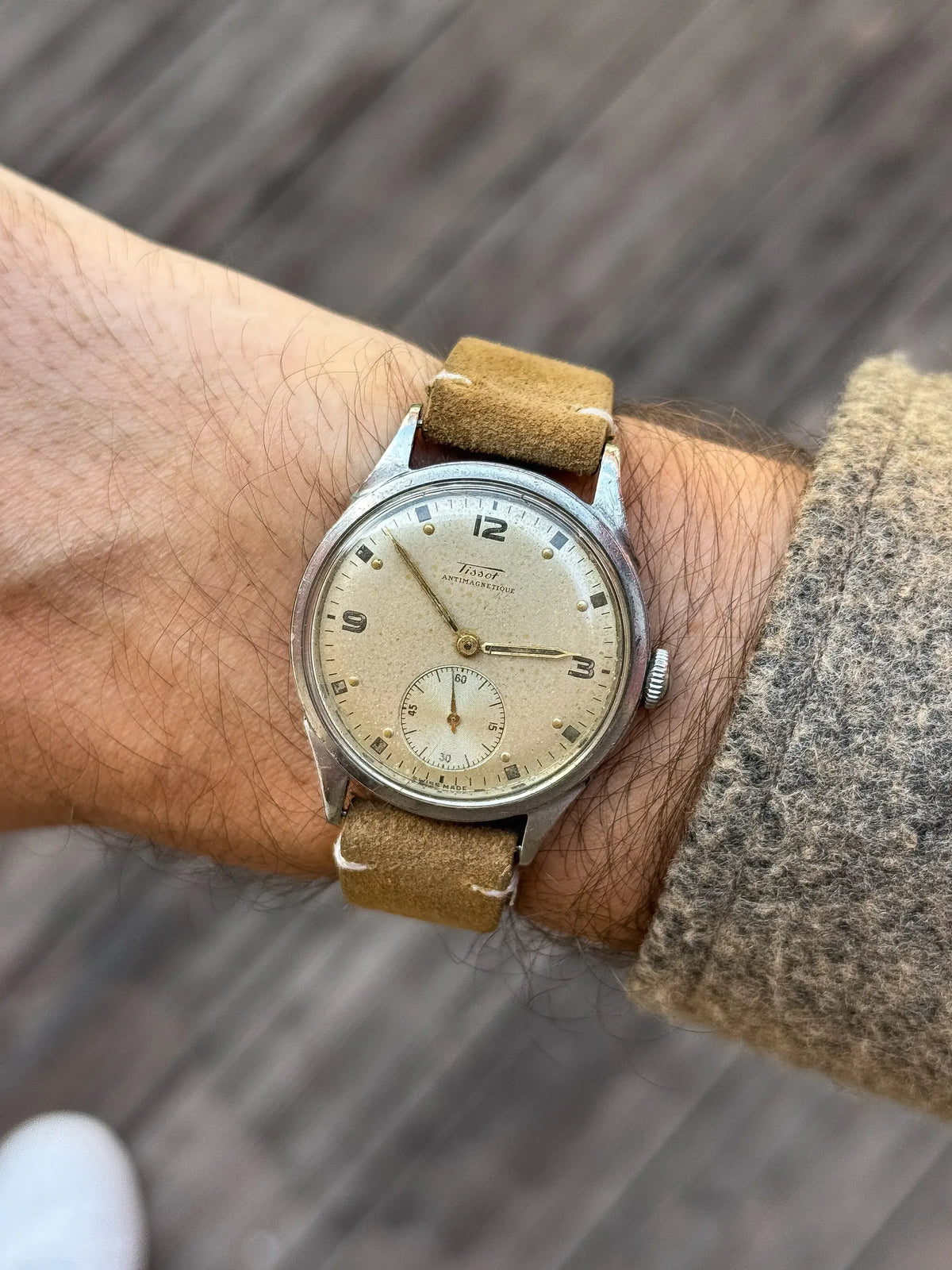 Vintage Tissot Antimagnetique watch with cream dial, steel case, and tan suede strap worn on wrist