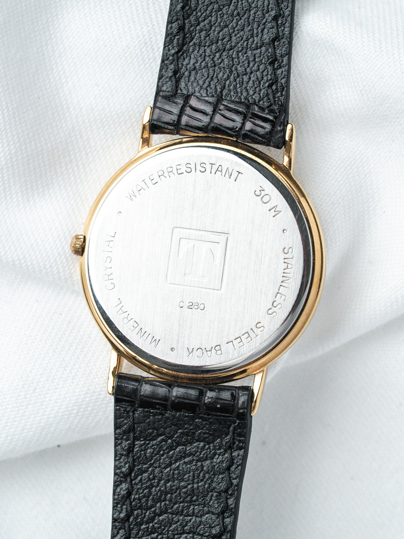 Vintage watch with gold case, black textured strap, stainless steel back, water-resistant 30M