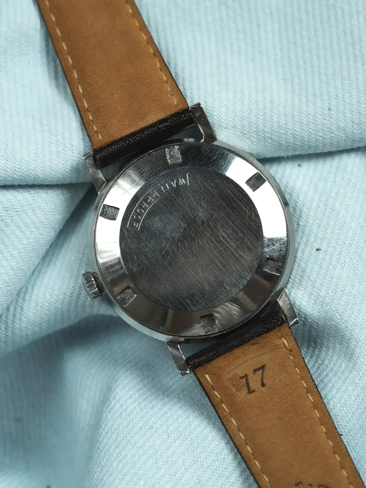 Vintage Omega watch back with stainless steel case and brown leather strap