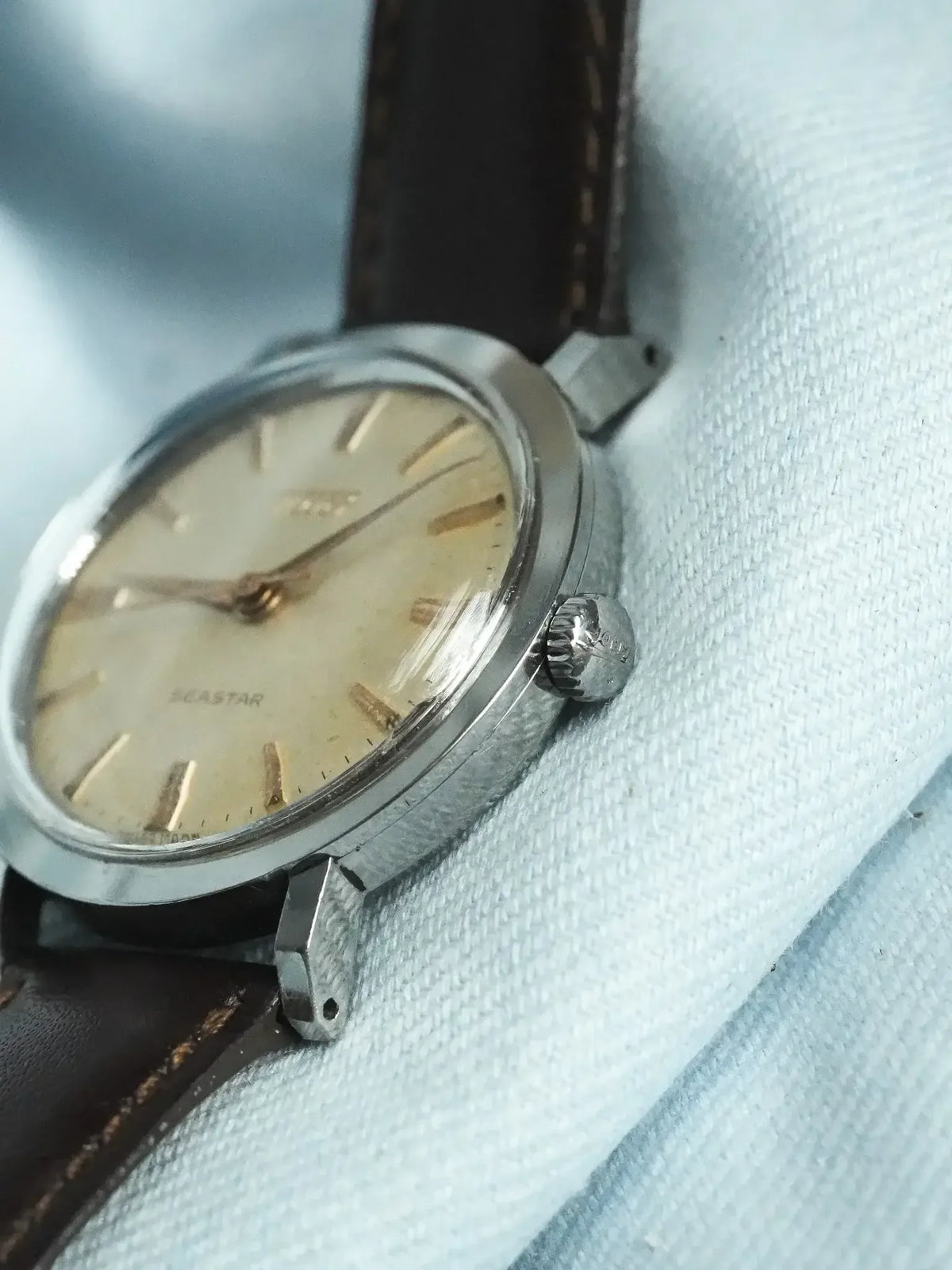 Vintage Doxa Seastar watch with cream dial, steel case, brown leather strap on textured fabric
