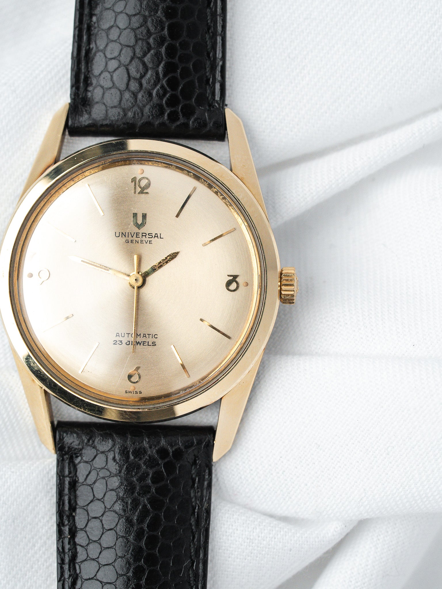 Universal Genève vintage watch with gold case, cream dial, black textured strap