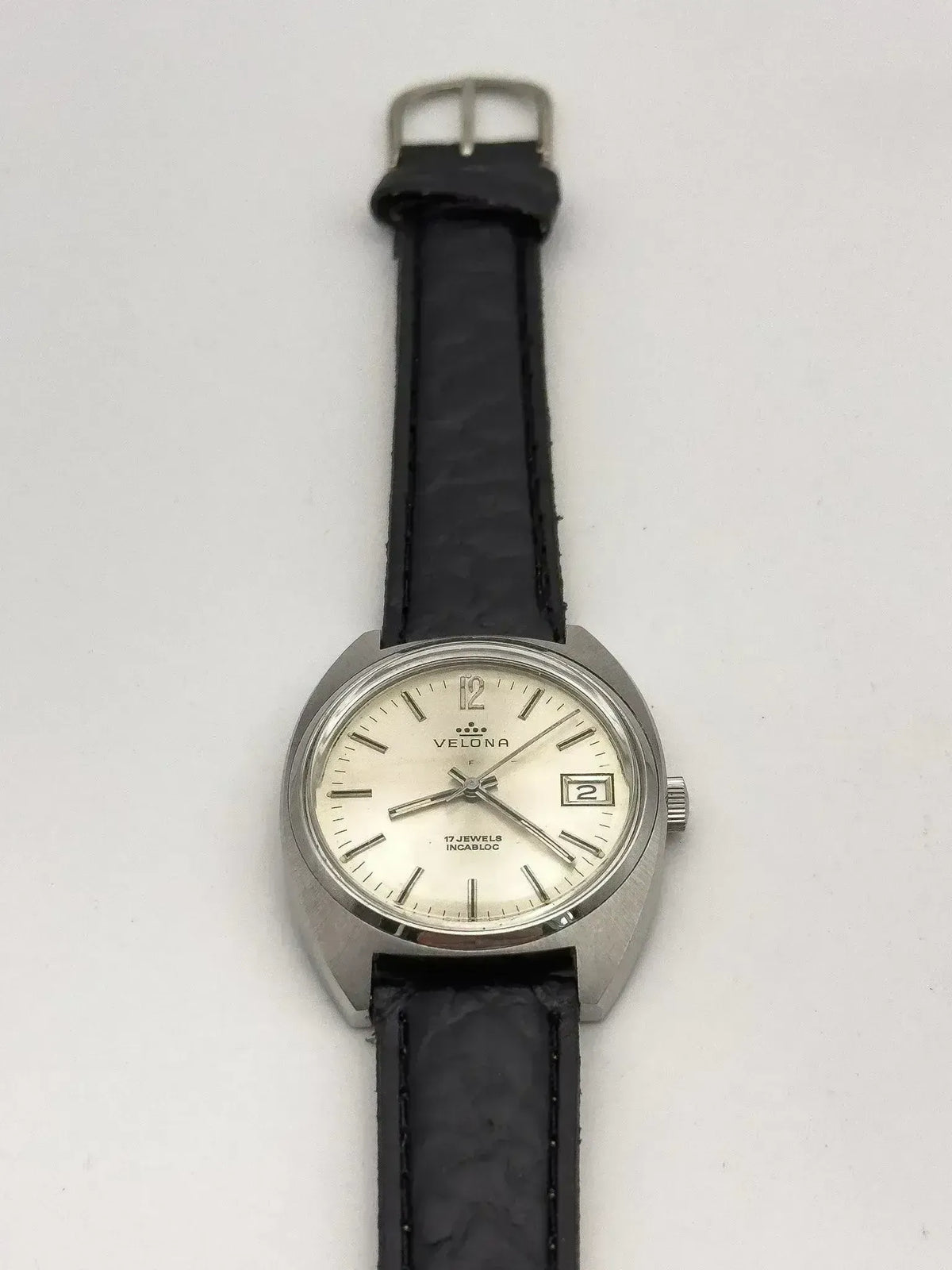 Velona vintage watch with silver case, cream dial, black leather strap on white background