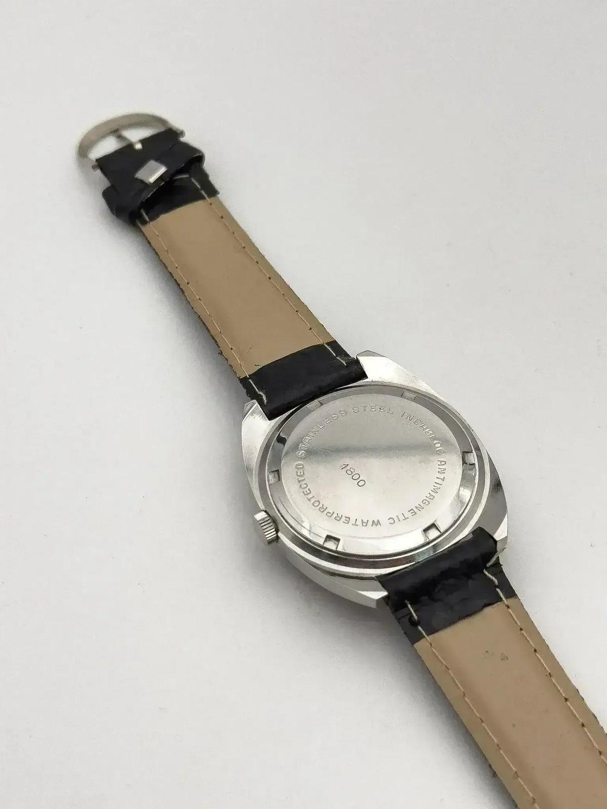 Vintage watch with stainless steel case, beige and black leather strap, back view