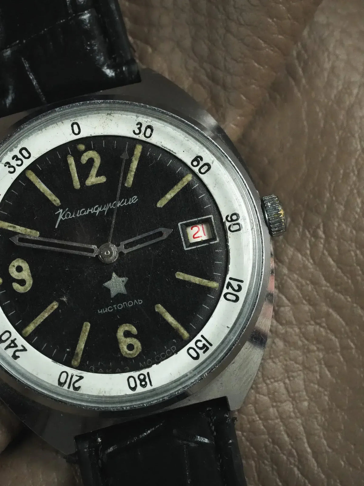 Vintage Komandirskie watch with black dial, luminous markers, and date window on leather strap
