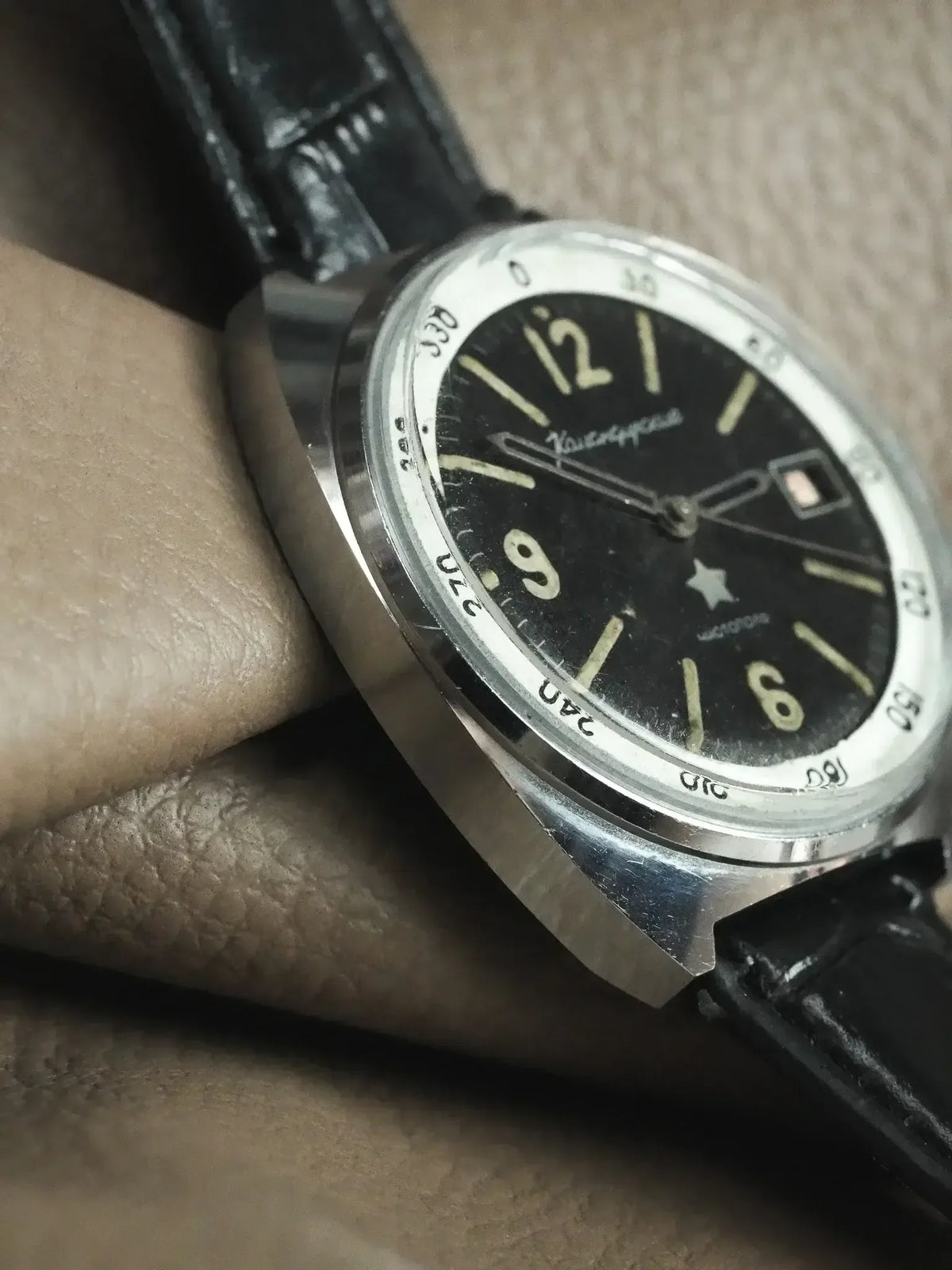 Vintage Vostok watch with black dial, white markers, and black leather strap