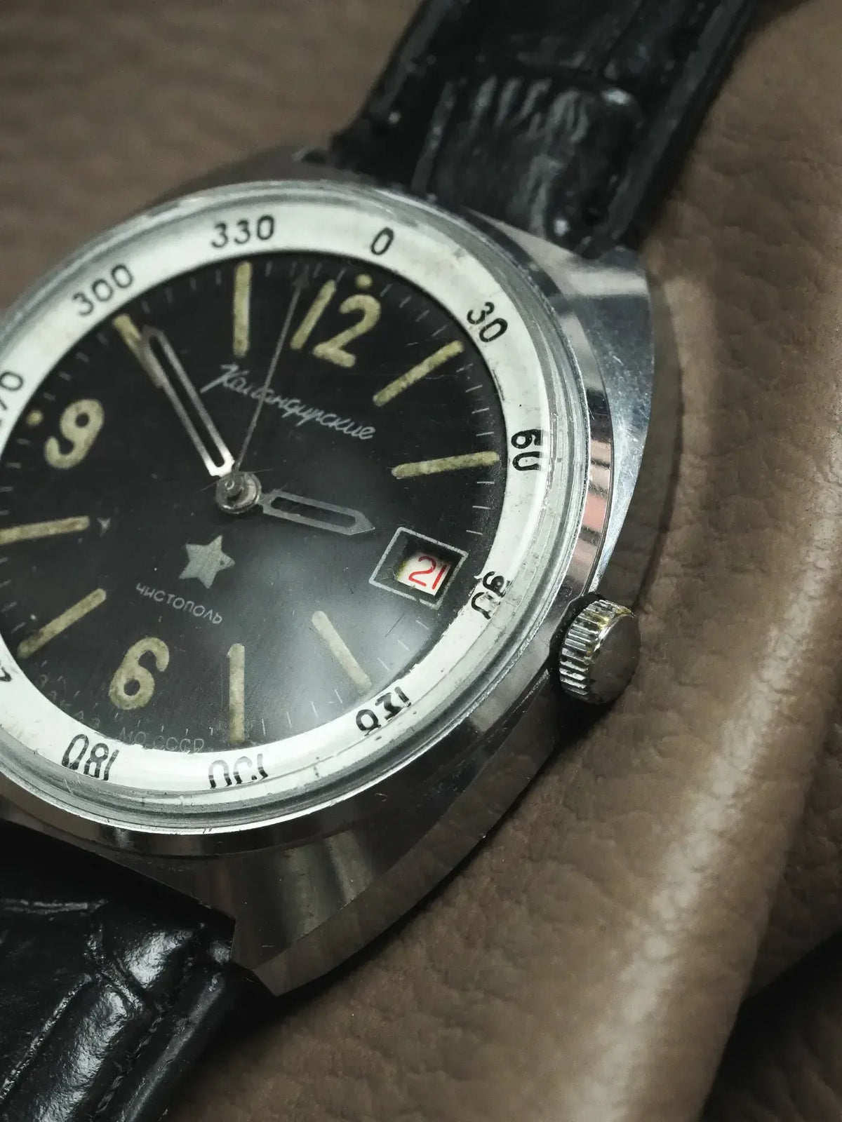 Vintage Vostok Komandirskie watch with black dial, luminous markers, date window, and black leather strap