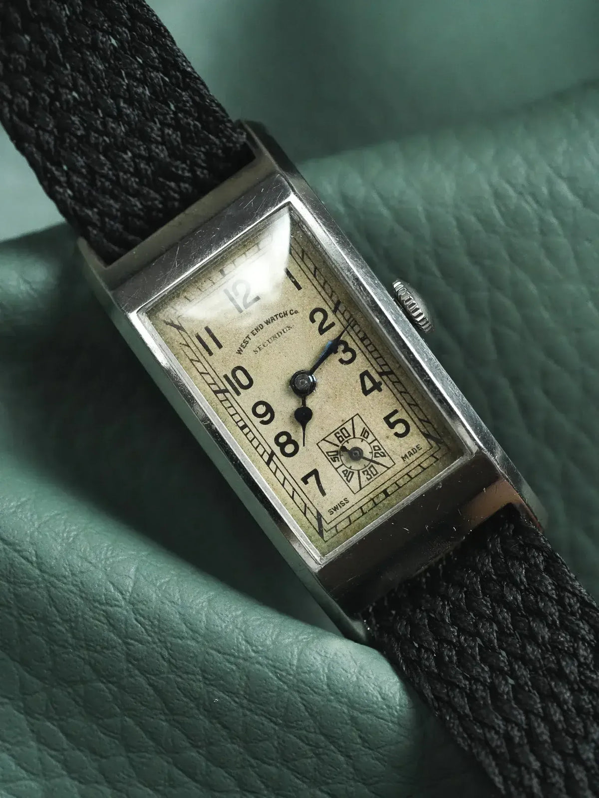 Vintage West End Watch Co. Secundus, rectangular silver case, cream dial, black fabric strap on green leather