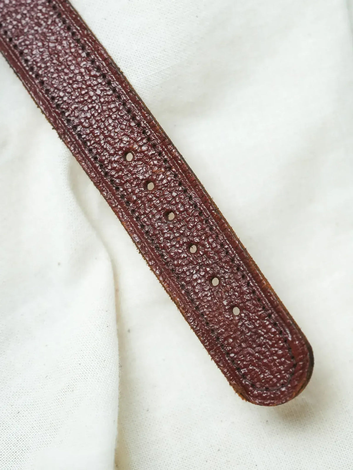 Vintage burgundy leather watch strap with textured grain and stitching detail