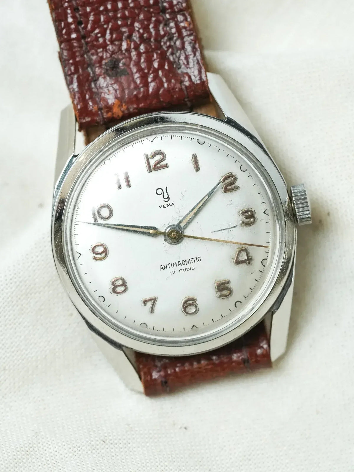 Vintage Yema antimagnetic watch with white dial, steel case, and brown leather strap