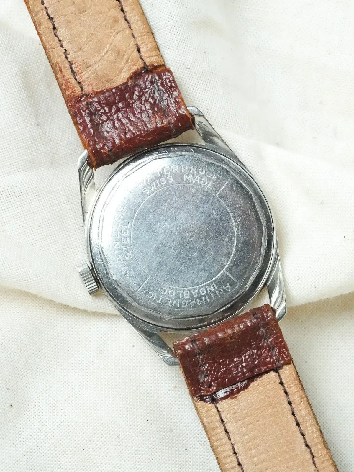 Vintage stainless steel watch back with waterproof Swiss Made engraving, brown leather strap