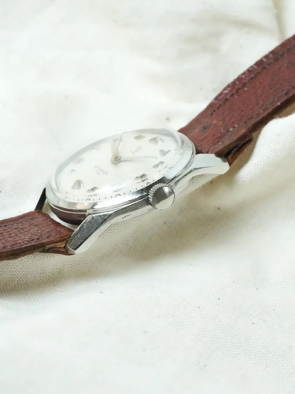Vintage IWC watch with white dial, steel case, brown leather strap on fabric