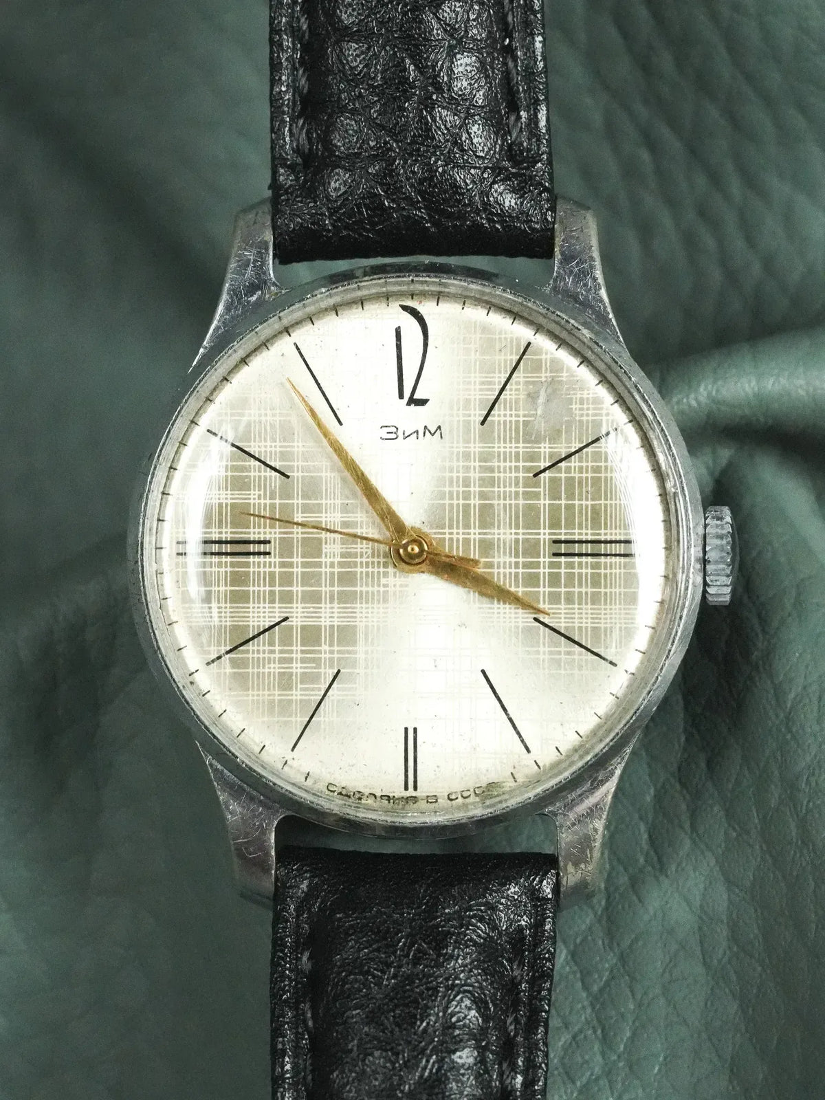 Vintage Zim watch with white dial, black leather strap, and gold hands