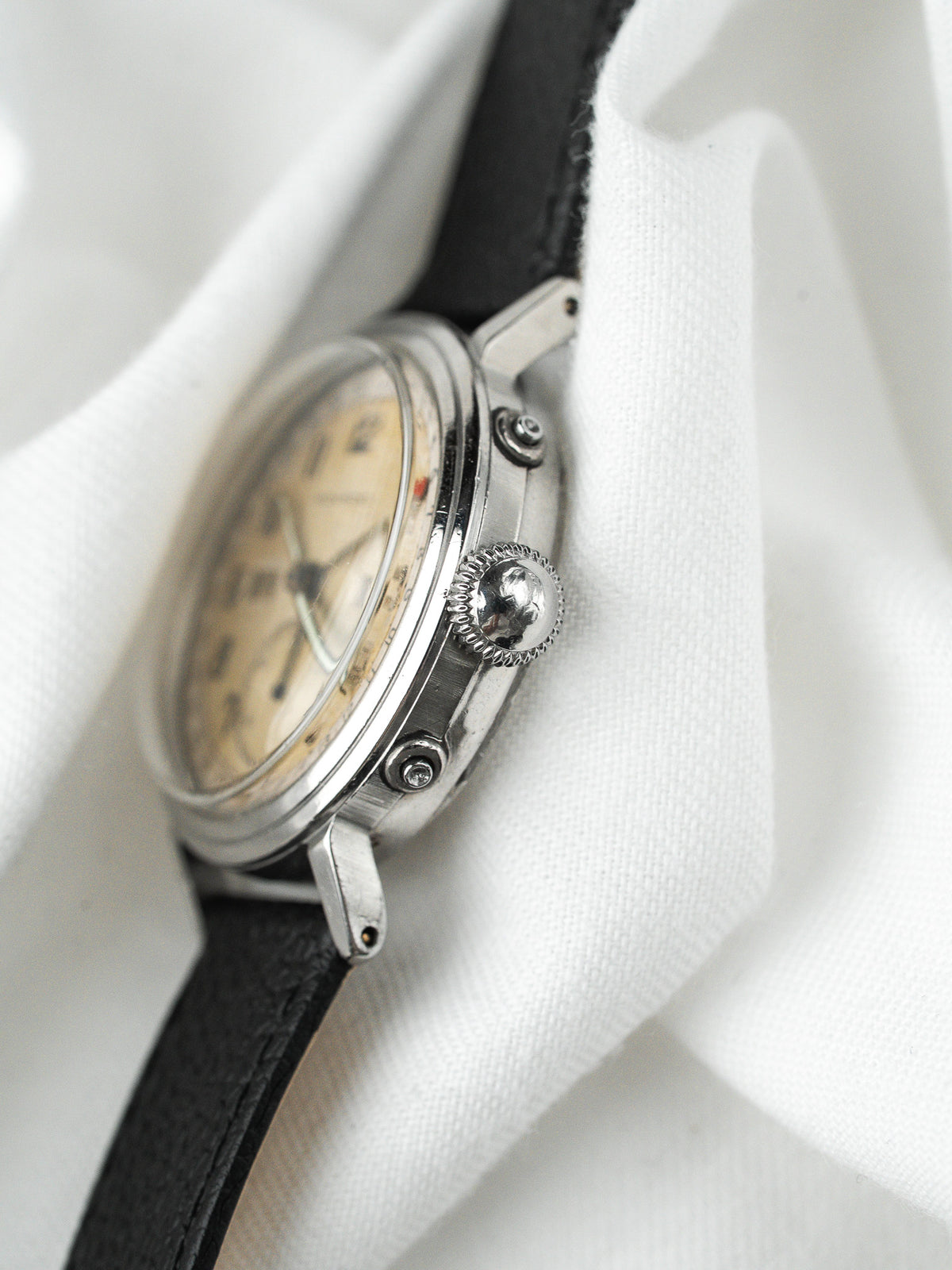 Montre vintage au boîtier acier, cadran beige et bracelet en cuir noir